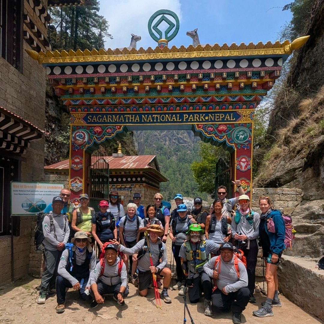 Group of hikers posing in front of a colorful Sagarmatha National Park entrance in Nepal.