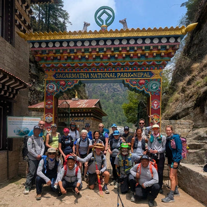 Group of hikers posing in front of a colorful Sagarmatha National Park entrance in Nepal.