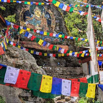 Stupa with colorful prayer flags and Buddha statue in a forested area